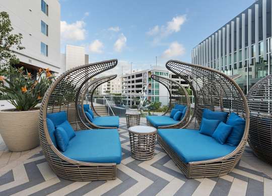 Two blue cushioned chairs and a table are on a patio.