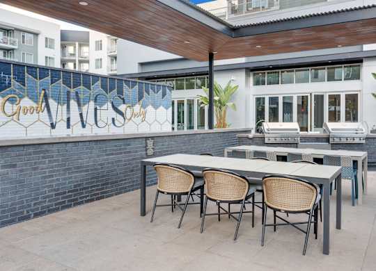 A patio with a table and chairs is in front of a building with a sign that says Good Vibes Only.