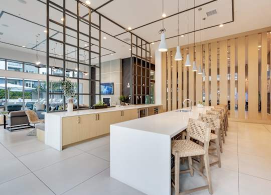 A modern kitchen with a white counter and chairs.