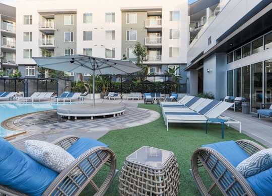 A round pool surrounded by lounge chairs and umbrellas.