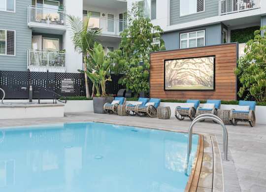 A pool with lounge chairs and a painting on a wall.