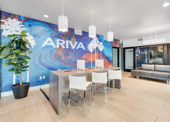 A white desk with chairs in front of a wall with the word ARIVA on it.