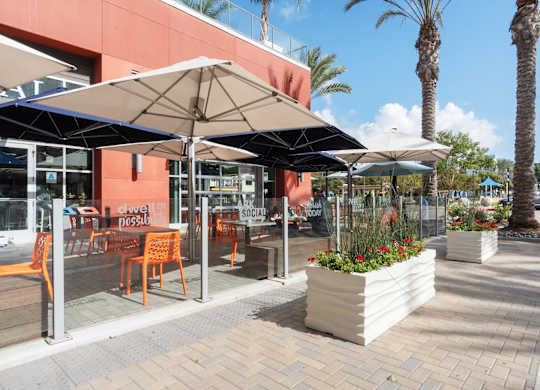 A sunny day at a cafe with orange chairs and umbrellas.