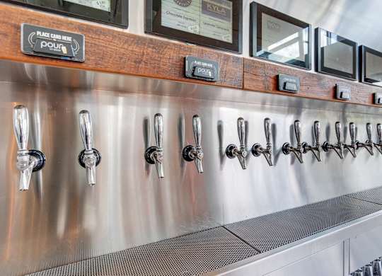 A stainless steel beer tap line with a wooden board above it.