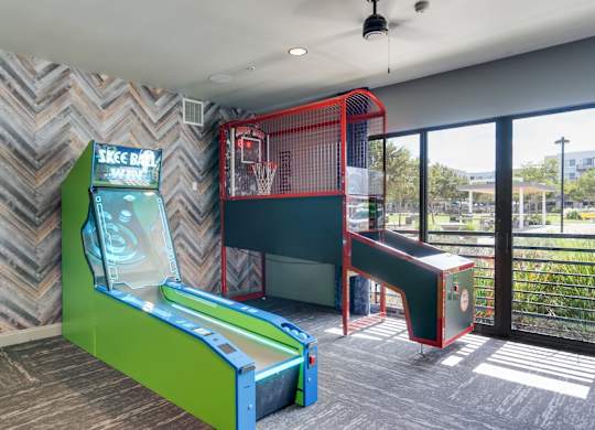 A room with a green and red arcade game and a basketball hoop.