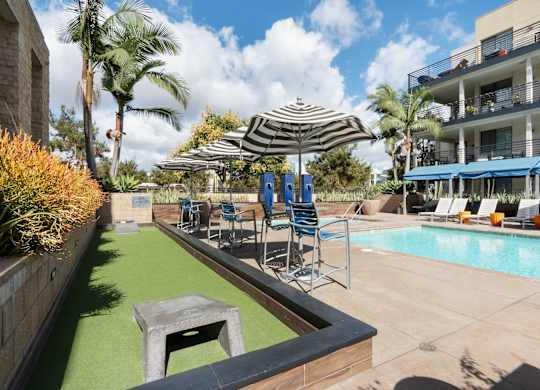 A pool area with a green pool mat and a striped umbrella.