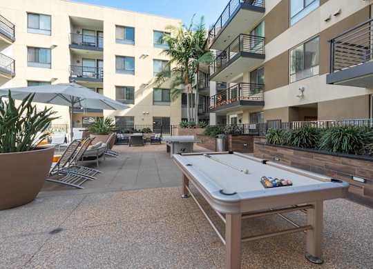 A pool table is in the middle of a courtyard surrounded by buildings.