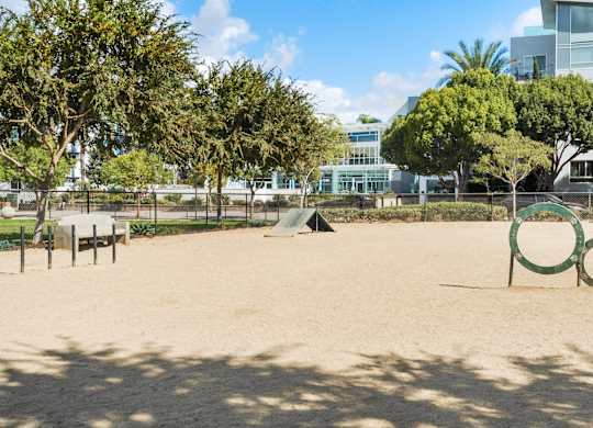 A playground with a sandy area, a slide, and a green ring.