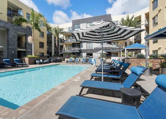 A swimming pool surrounded by blue lounge chairs and umbrellas.