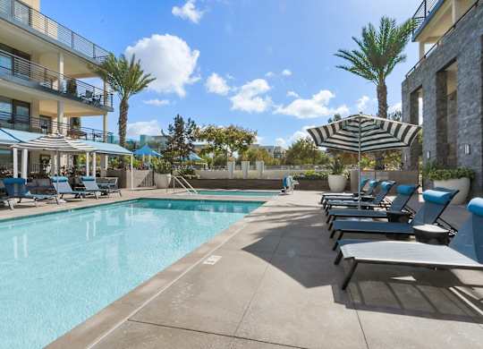 A pool area with sun loungers and a striped umbrella.