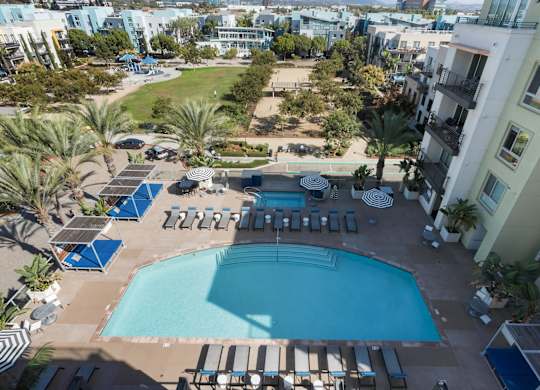 A large swimming pool surrounded by sun loungers and umbrellas.