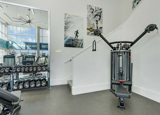 A gym with a weightlifting machine in the foreground.