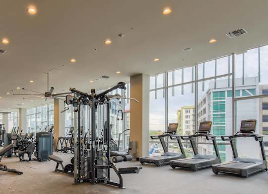 A gym with a variety of equipment including treadmills, weights, and exercise machines.
