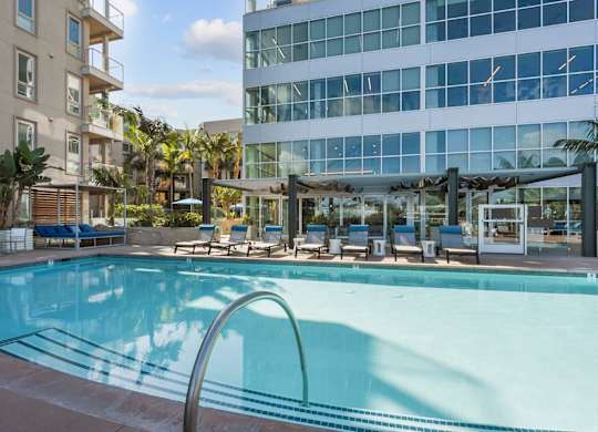 A swimming pool with a metal railing and chairs around it.