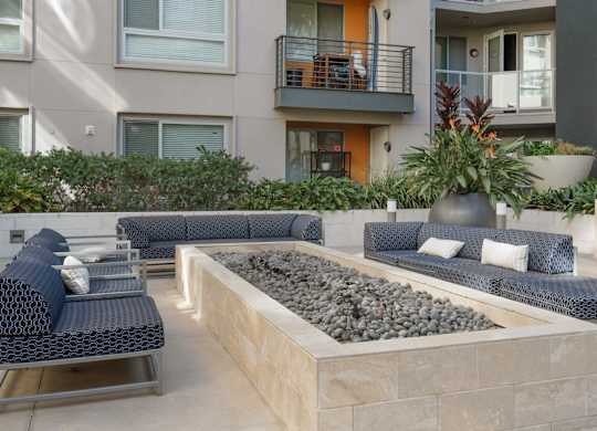 A patio with a couch, chairs, and a fire pit.