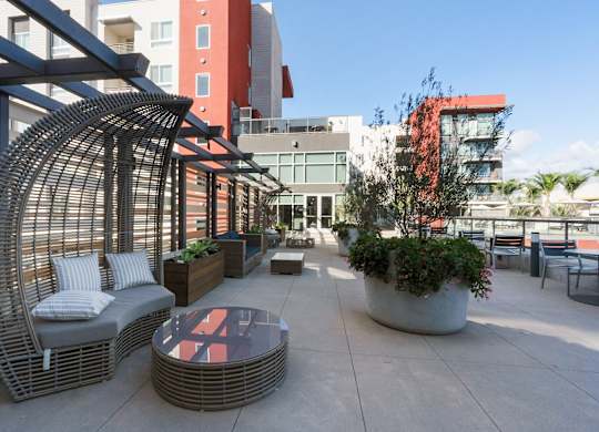 A patio with a wicker chair and table.