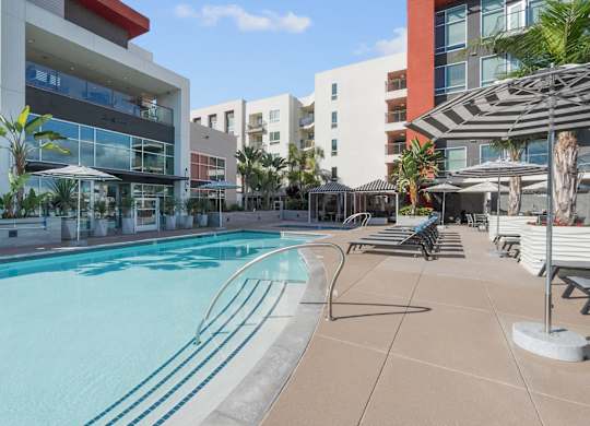 A swimming pool surrounded by lounge chairs and umbrellas.