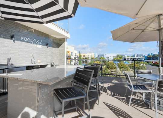 A pool bar with a striped umbrella and chairs.
