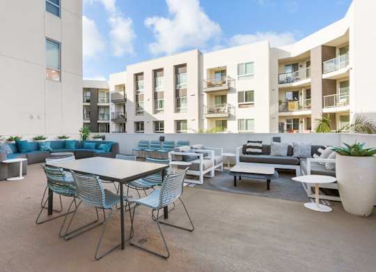 A patio with a table and chairs is surrounded by apartment buildings.