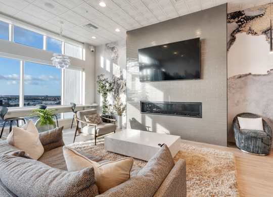 A modern living room with a large couch, a fireplace, and a flat-screen TV mounted on the wall.