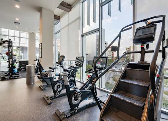 A gym with a treadmill, elliptical machines and a stair climber.