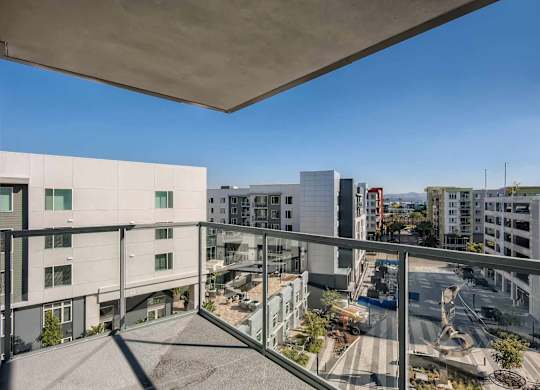 A view from a balcony overlooking a parking lot and buildings.