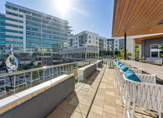 A sunny day at a modern building with a balcony and chairs.