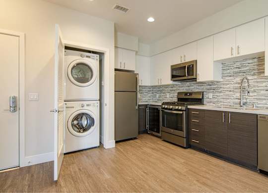 A modern kitchen with a washer and dryer built into the cabinetry.
