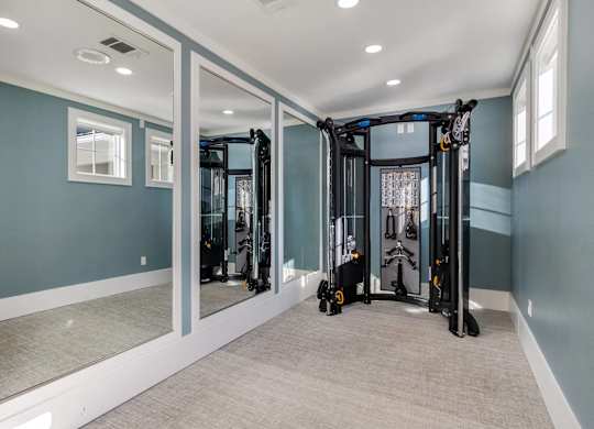 A spacious home gym with a mirrored wall and a treadmill.