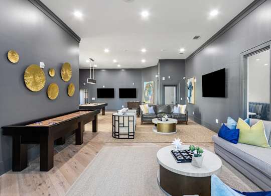 A modern living room with a pool table and a grey sofa.