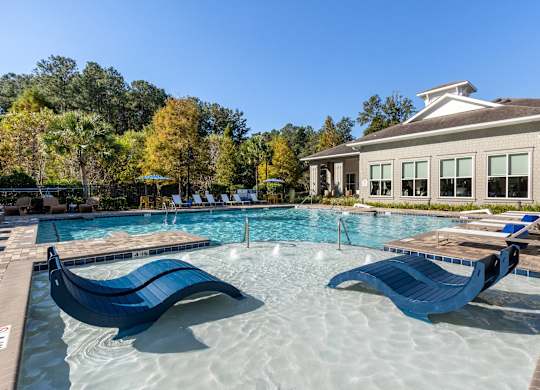 A large swimming pool with a slide and a building in the background.