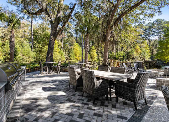 A patio with a table and chairs surrounded by trees.