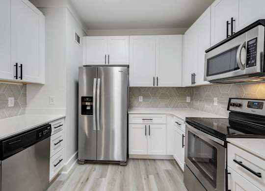 A kitchen with a stainless steel refrigerator and black and white cabinets.