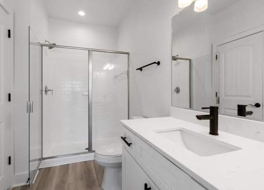 A white bathroom with a toilet, sink, and shower.