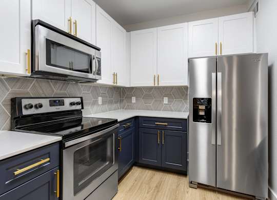 Apartments in Charleston, SC, with In-Unit Washer and Dryer - The Avenues at Verdier Pointe - Kitchen with Wood-Style Flooring, Two-Tone Cabinetry, Range, French Door Refrigerator, and Mounted Microwave.