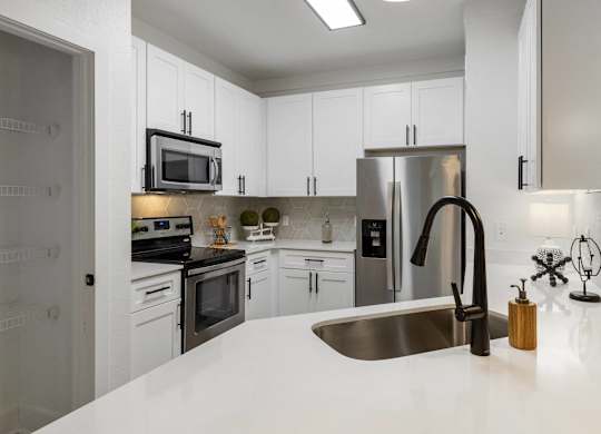 A modern kitchen with white cabinets and stainless steel appliances.