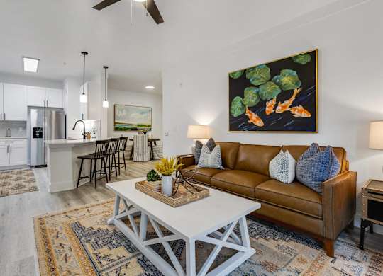 A living room with a brown couch and a painting of broccoli on the wall.