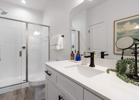 A white bathroom with a glass shower door and a white toilet.