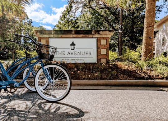 A blue bicycle is parked in front of a sign that says The Avenues at Vedder Point.