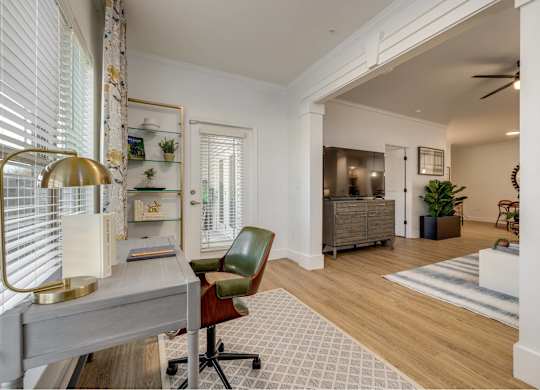 A room with a desk, chair, and a lamp.