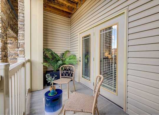 A patio with a chair, table, and potted plant.