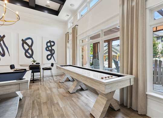 A pool table is in the middle of a room with a wooden floor and a window.