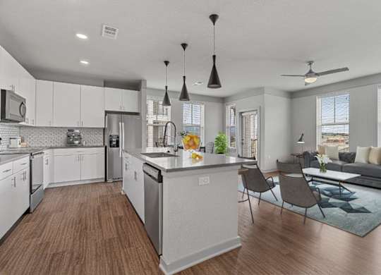 A modern kitchen with white cabinets and a wooden floor.
