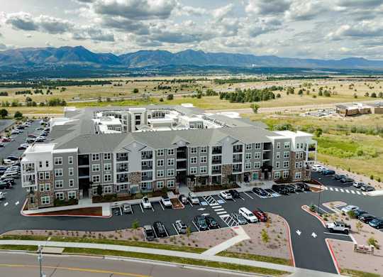 A large apartment complex with a parking lot in front.