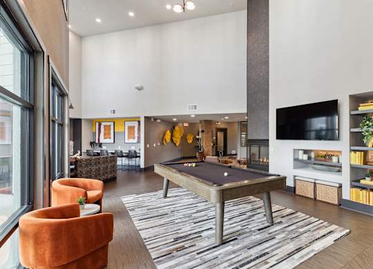 A living room with a pool table and a television.