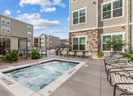 A swimming pool surrounded by lounge chairs and apartment buildings.
