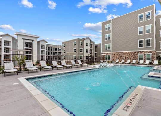 A swimming pool surrounded by lounge chairs and buildings.