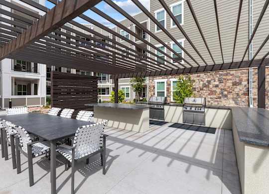 A patio with a table and chairs under a wooden pergola.