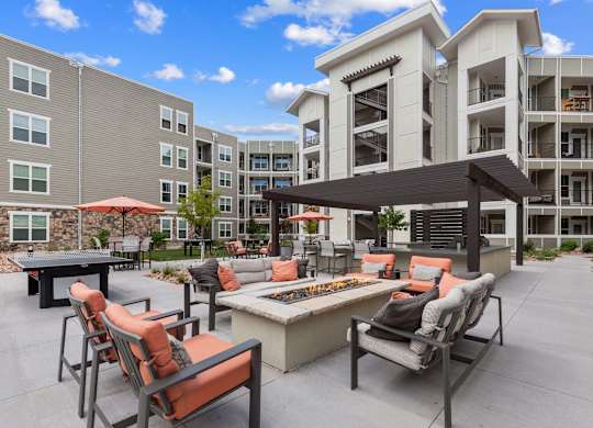 A patio with chairs and a table is surrounded by apartment buildings.