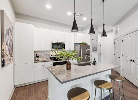 A kitchen with a white counter and bar stools.